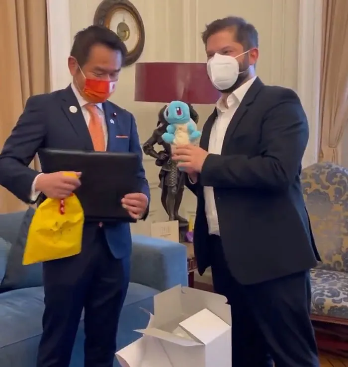 World leaders exchanging gifts and smiling indoors while wearing masks