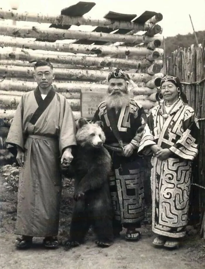 A black and white photo of three individuals with a small bear, an interesting photo still intact after all these years.