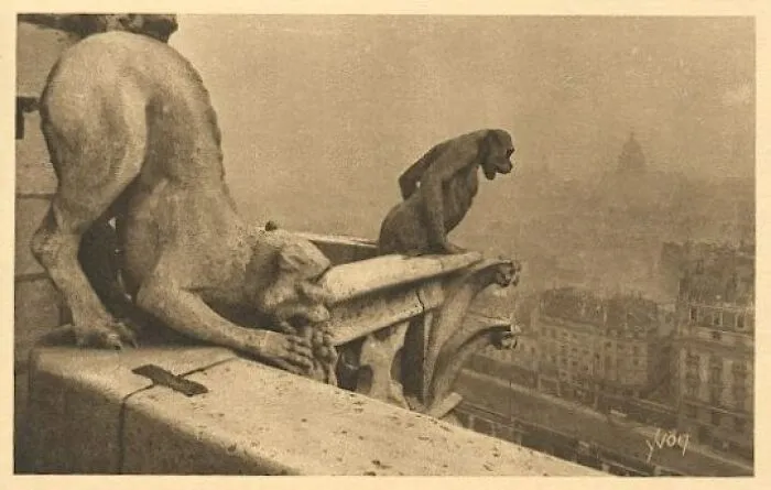 A sepia-toned image of gargoyles still intact, overlooking a distant city on a hazy day. The interesting objects highlight impressive preservation.