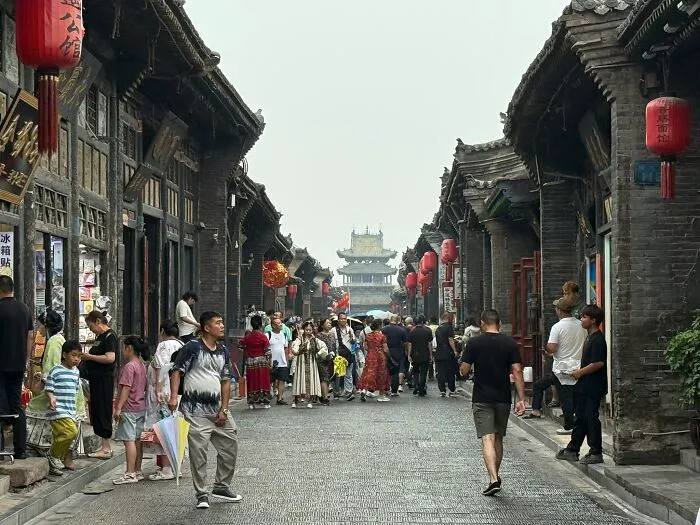 A bustling street scene in China with traditional architecture and many people, captured by a traveler.