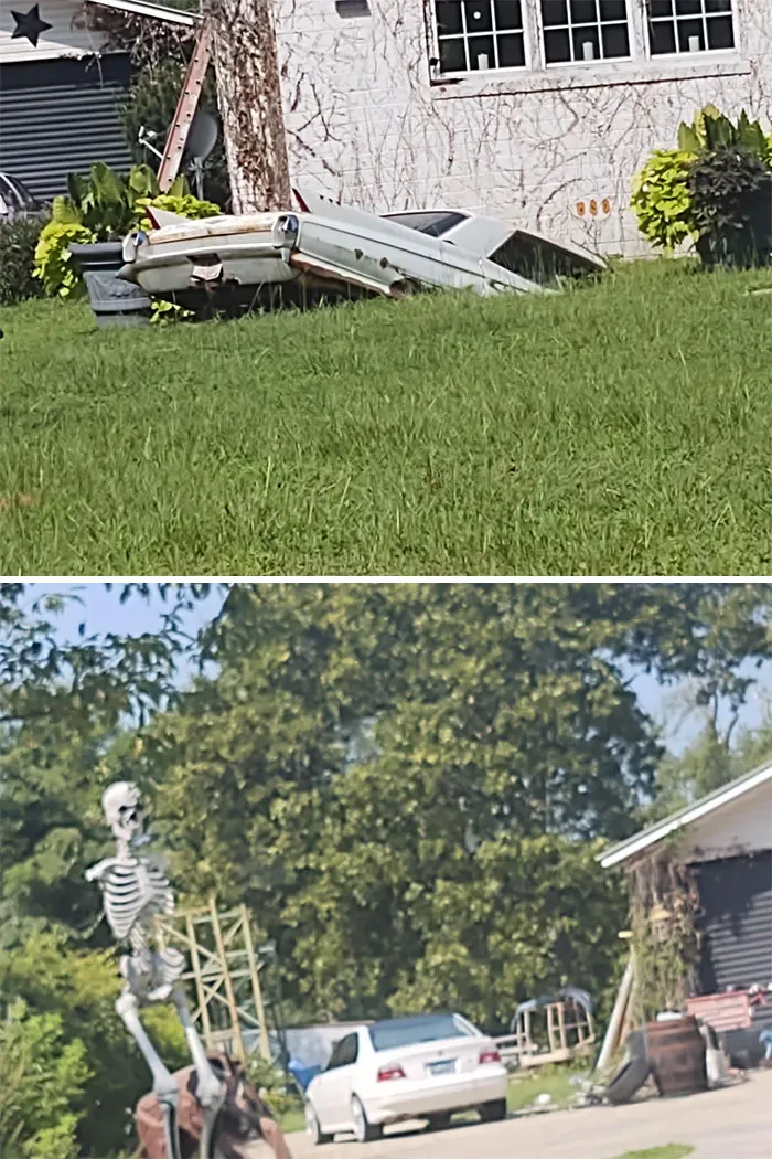 Vintage car partially buried in grass outside house in unusual scene
