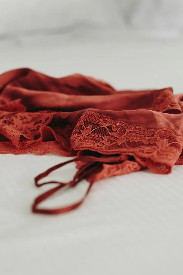 A red lace slip and matching top laying on a white bed, representing a romantic turn off for some men.