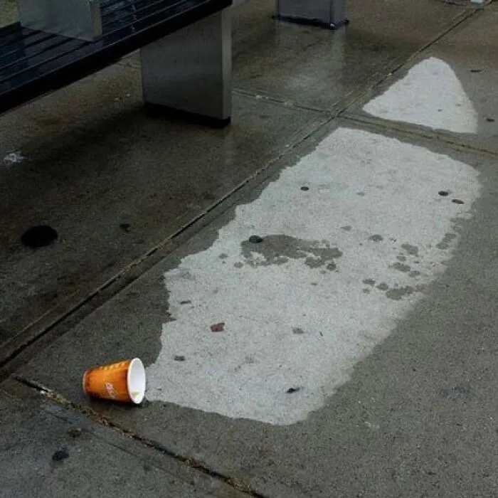 Spilled coffee creating wet stain resembling a footstep on concrete floor