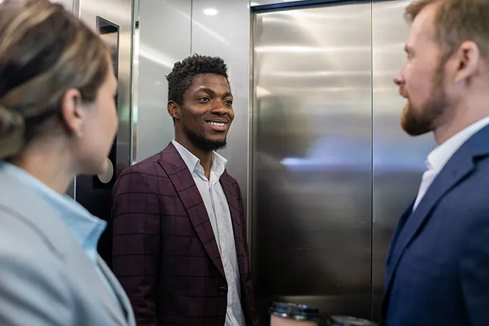 Smiling man socializing with colleagues inside elevator