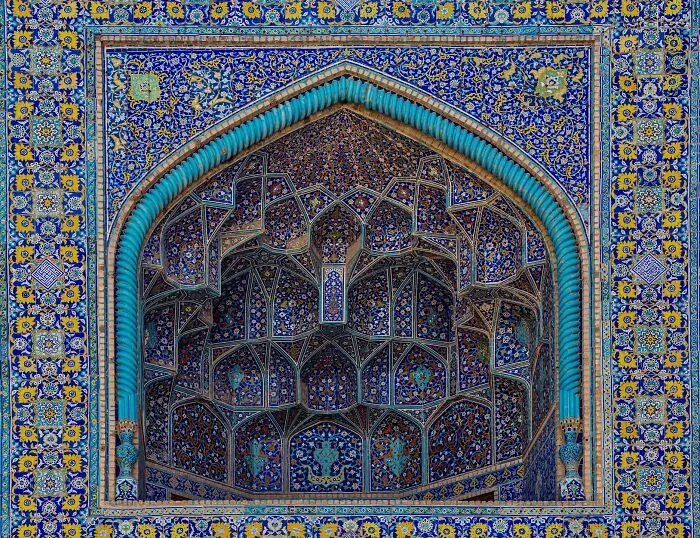 Blue and yellow classical Persian tilework framing a detailed niche with complex geometric patterns