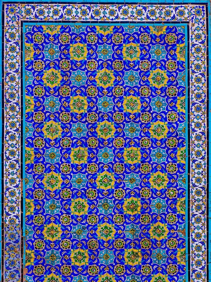 Intricate blue and yellow Persian tile patterns with geometric floral designs