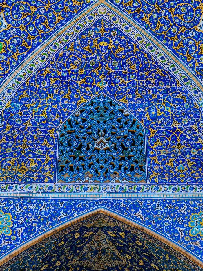 Detailed Persian tilework with blue and gold arabesque patterns on mosque wall