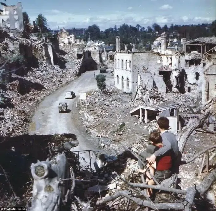 Tras el desembarco de Normandía, dos niños observan desde una colina cómo los soldados estadounidenses atraviesan la ciudad de Saint-Lô. Francia, 1944.