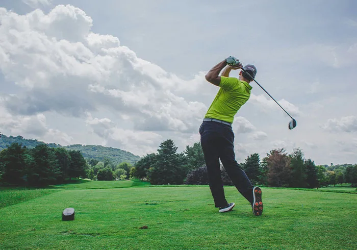 Golfer swinging club on green course under cloudy sky with cool facts