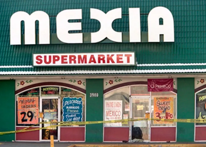 Exterior of Mexia supermarket with various colorful signs in windows