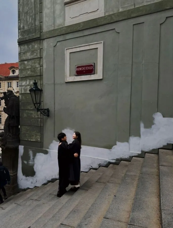 A couple embracing on stone steps, captured in the 'Like A Painting' photo trend between strangers.