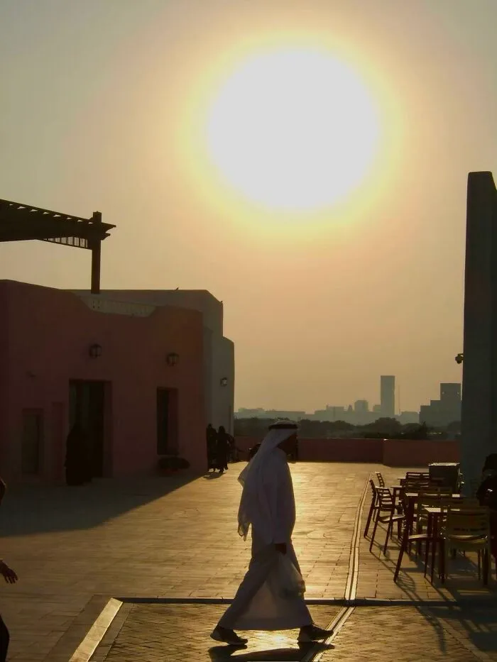 A wholesome photo of a person in traditional attire walking under a bright sun, a beautiful example of the photo trend.