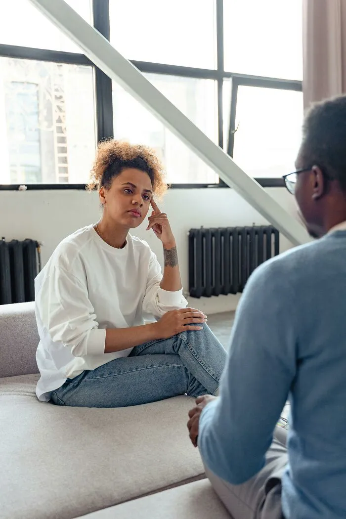 Woman thoughtfully listening during a serious discussion with man indoors