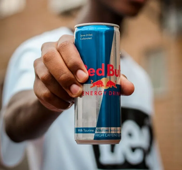Hand holding a Red Bull energy drink, symbolizing a quick fix for intense stress and burnout.