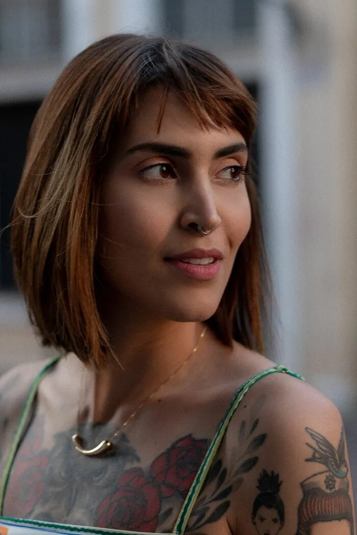 A woman with a nose ring and shoulder tattoos looks away, her style potentially being a turn off for some men.