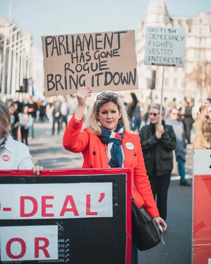 A woman holding a sign in a crowd, rolling her eyes at mens turn-offs.