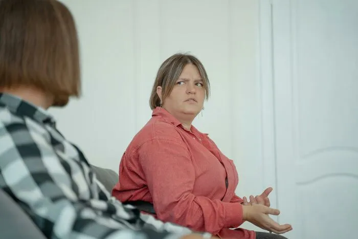 Woman in red shirt discussing seriously with another person