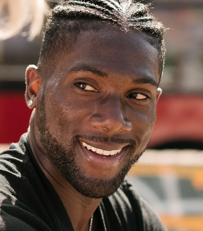 Smiling man with braided hair outdoors in casual setting