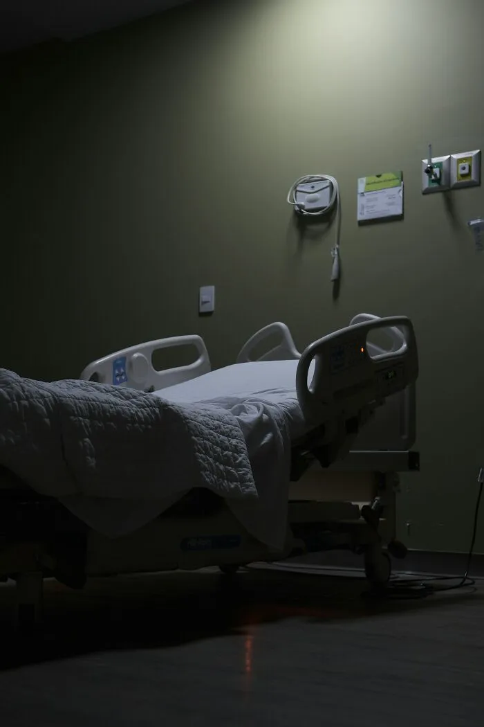 Empty hospital bed in dimly lit room at night for creepy hospital stories