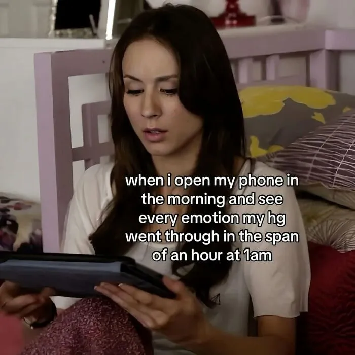 A woman looks intently at a tablet in bed, representing hilarious memes and relatable morning phone checks.