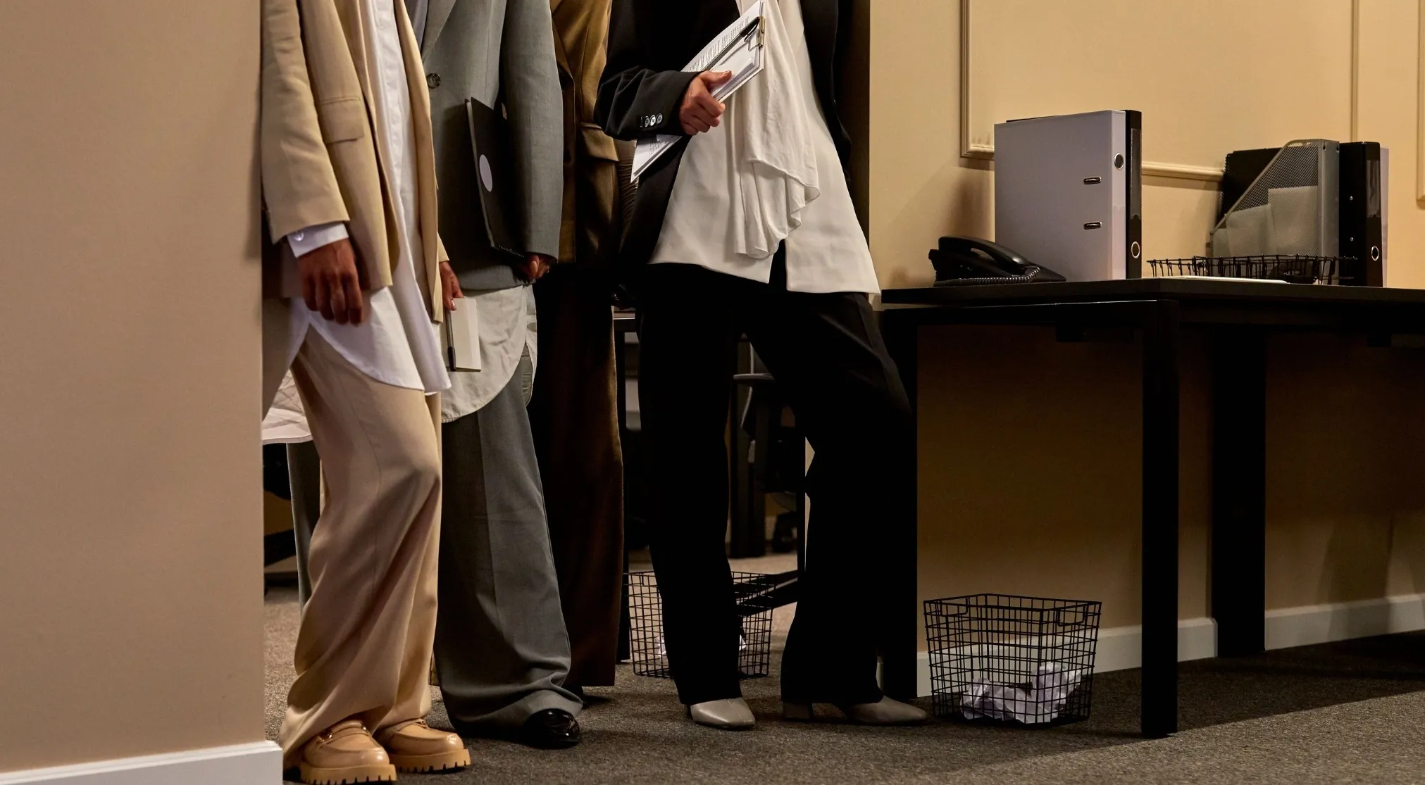 Three professionals in an office setting, one holding documents, hinting at job positions that support a manager.