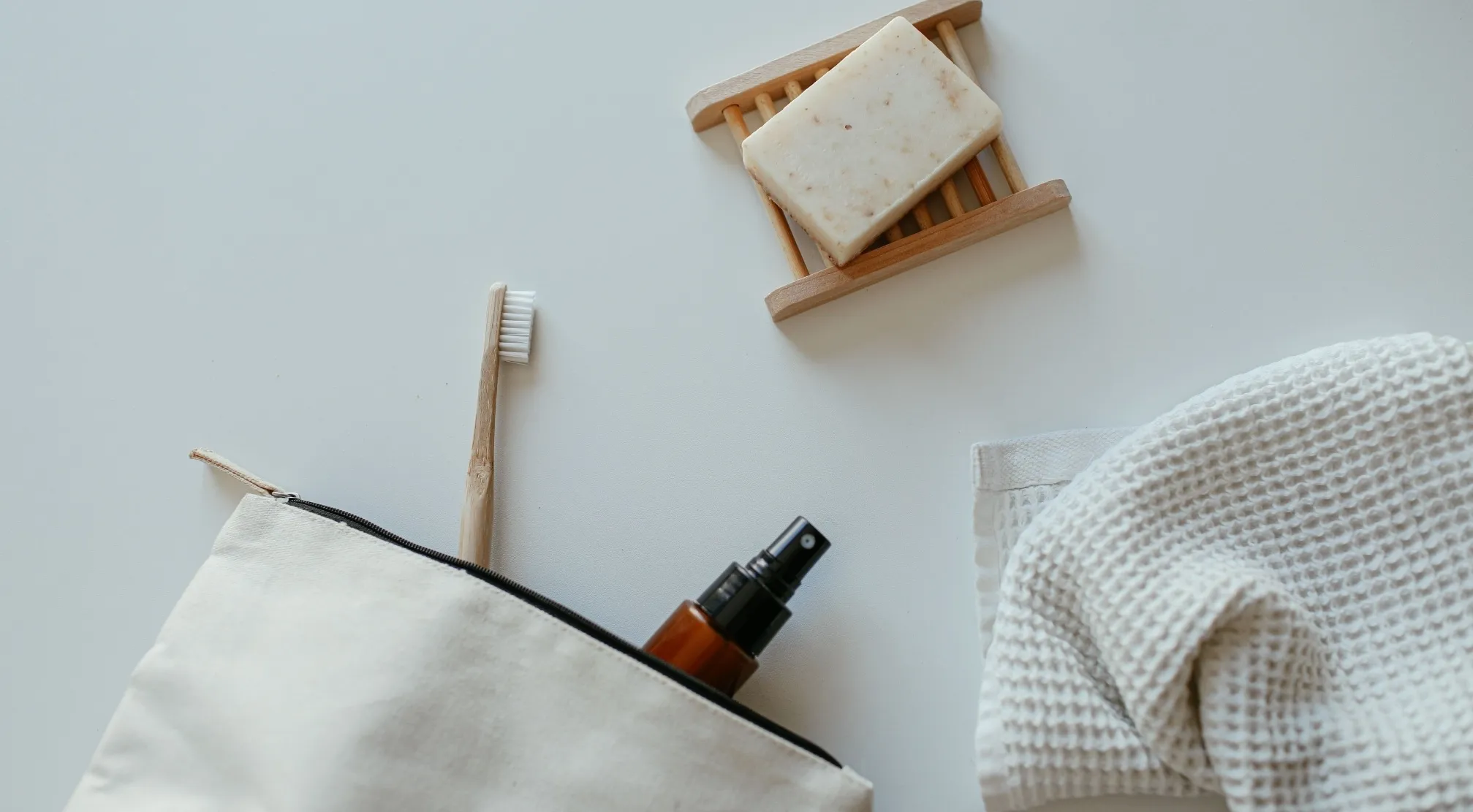 Zero-waste personal care products: toothbrush, bar soap on a wooden dish, small spray bottle, and washcloth. Antiperspirant alternative.