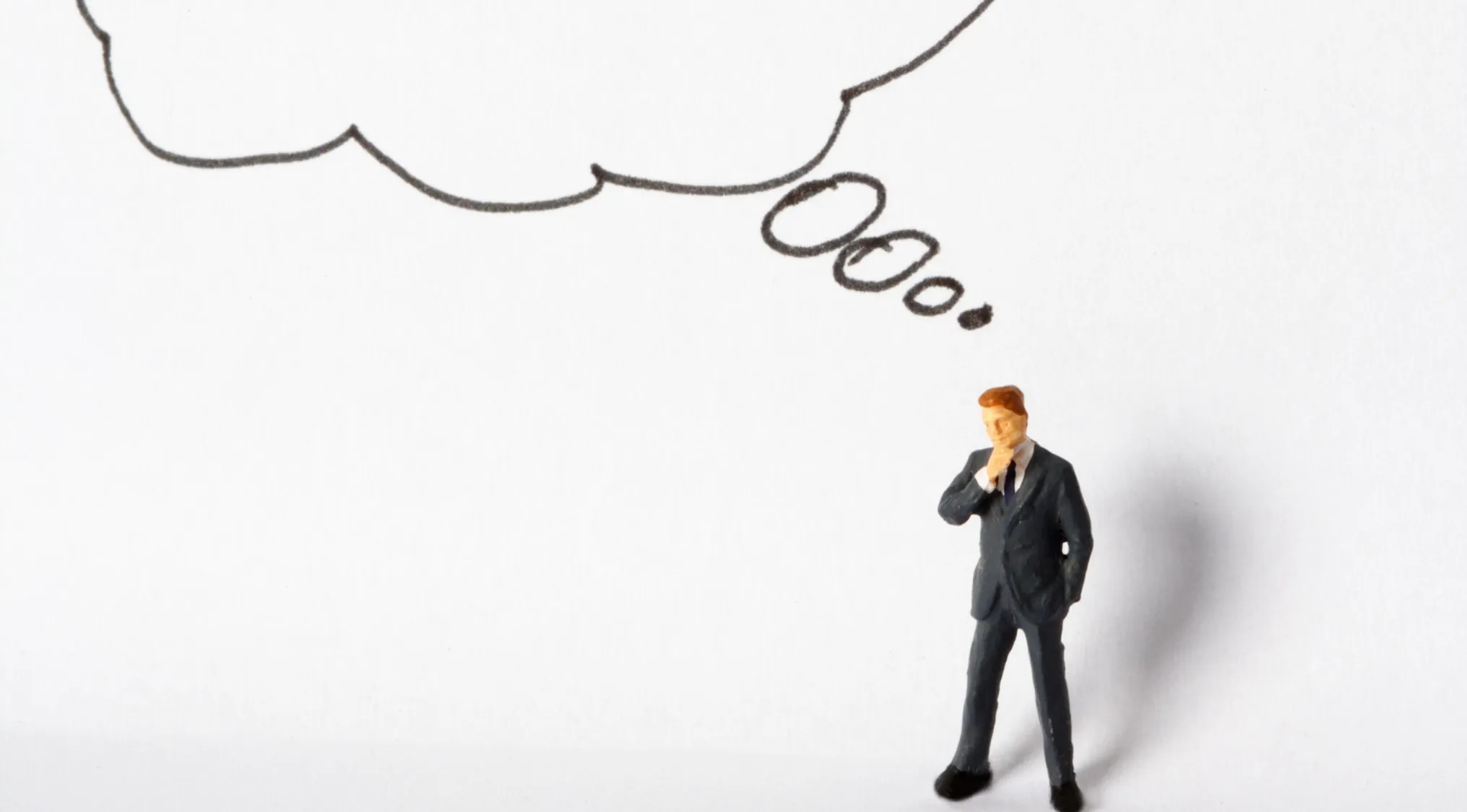 A miniature figure of a man in a suit with a thought bubble above his head, representing an ad hominem fallacy.
