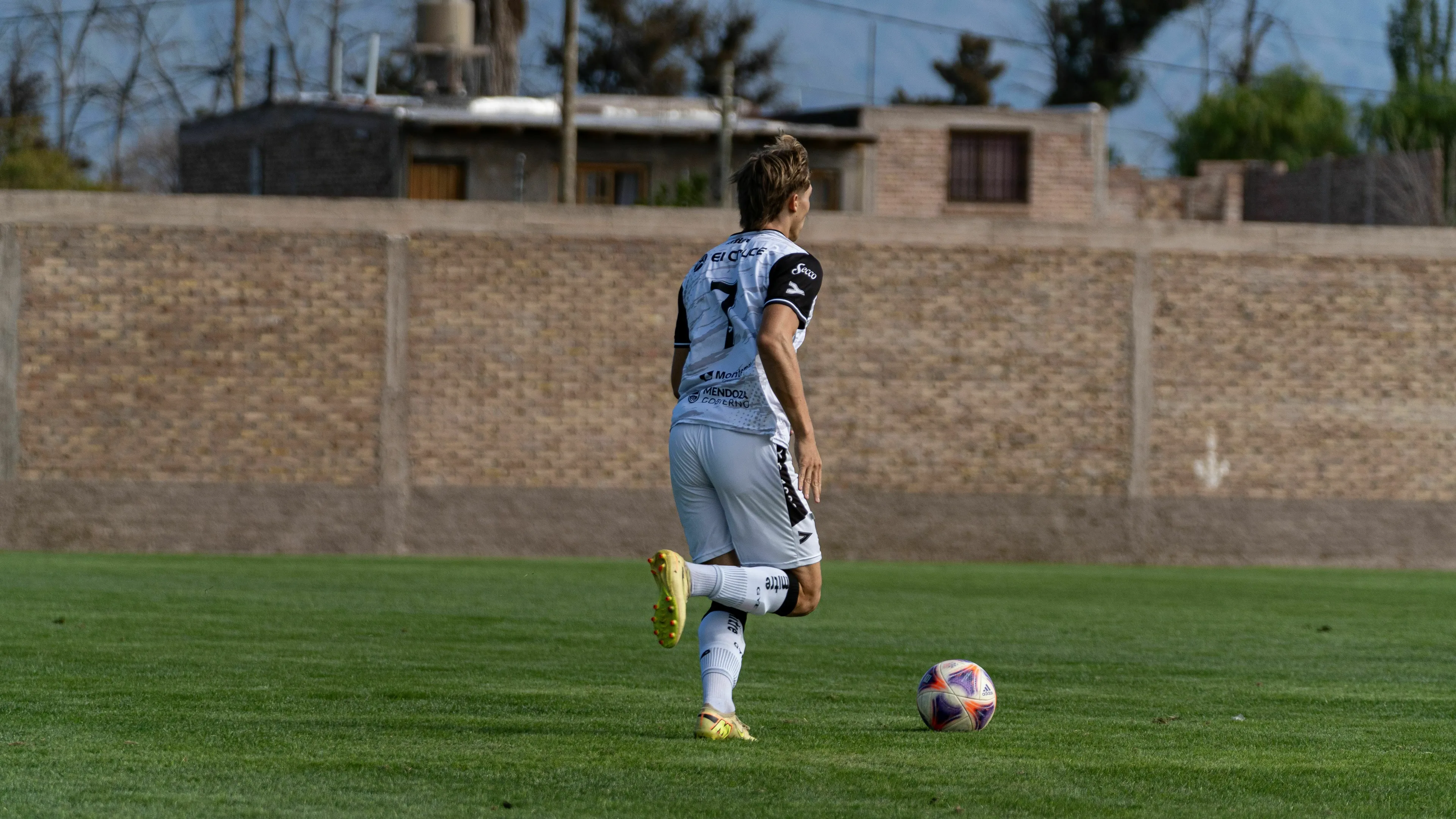 A soccer player with the ball on a field, contemplating his move, demonstrating risk taker decisions.