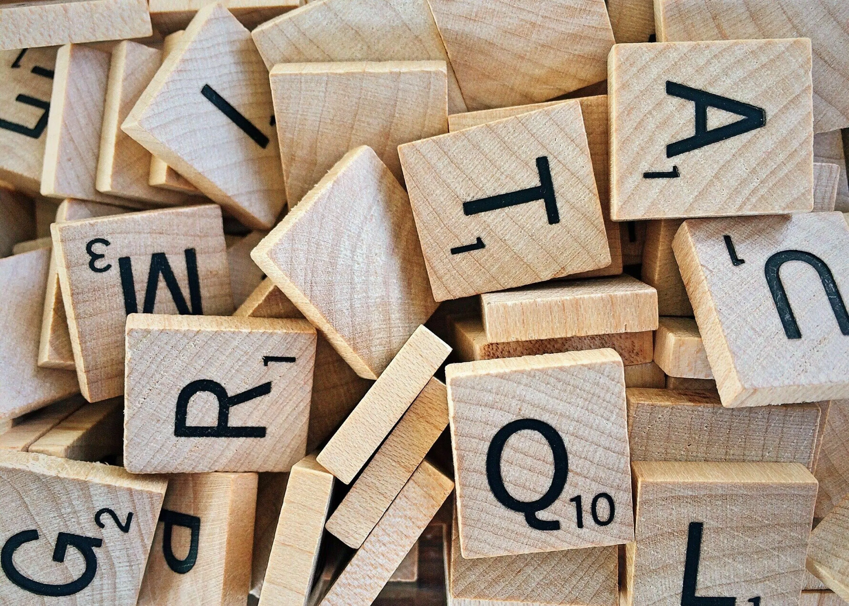 A pile of Scrabble tiles, with letters like Q, T, R, and A visible, representing choosing a motto and risk taker type.