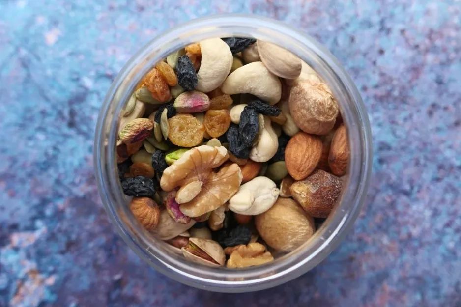 An overhead view of a jar filled with various nuts and dried fruits, ideal as a healthy road trip snack.