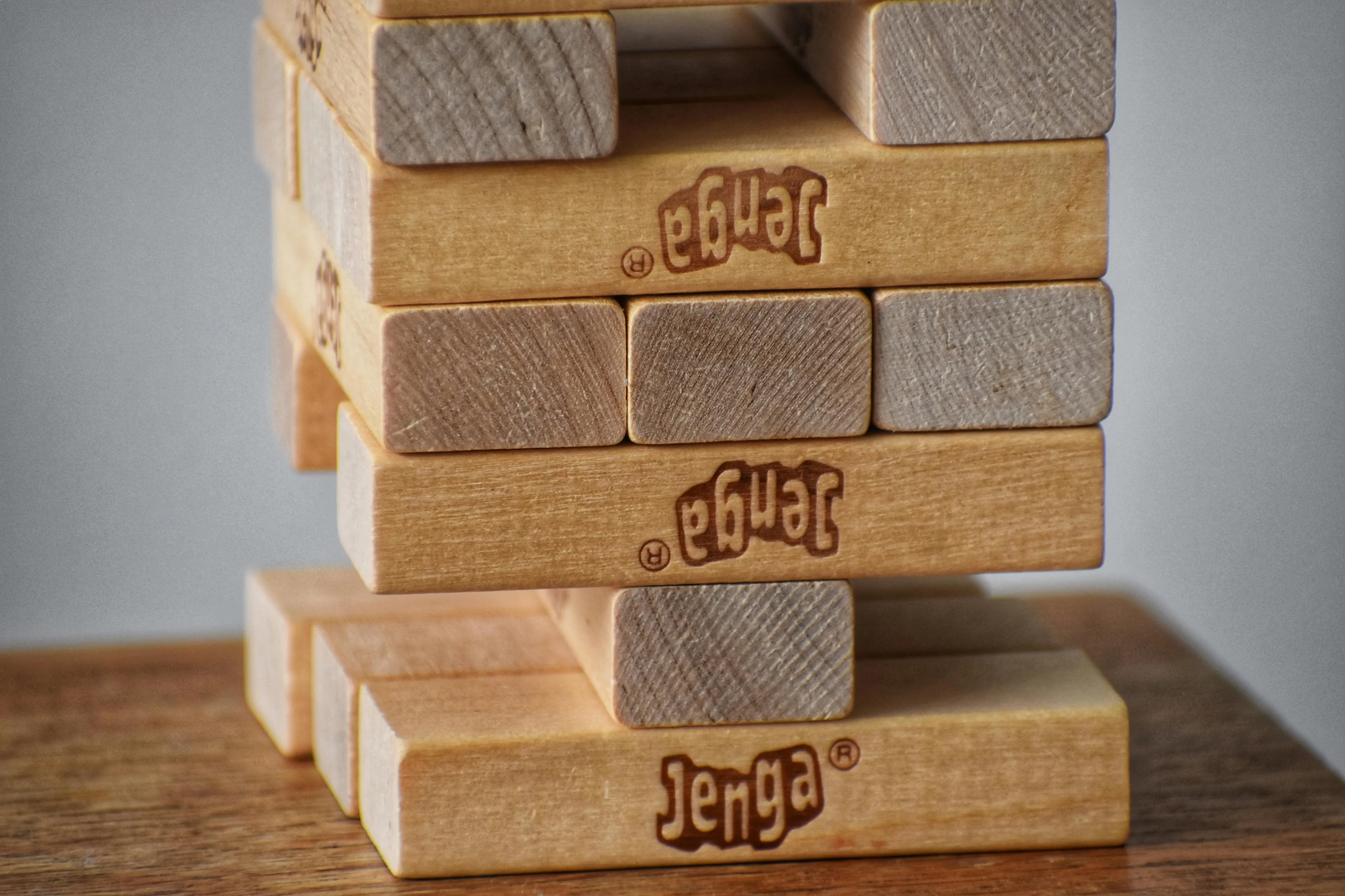 A close-up of a Jenga tower, with wooden blocks stacked precariously, ready for a game.
