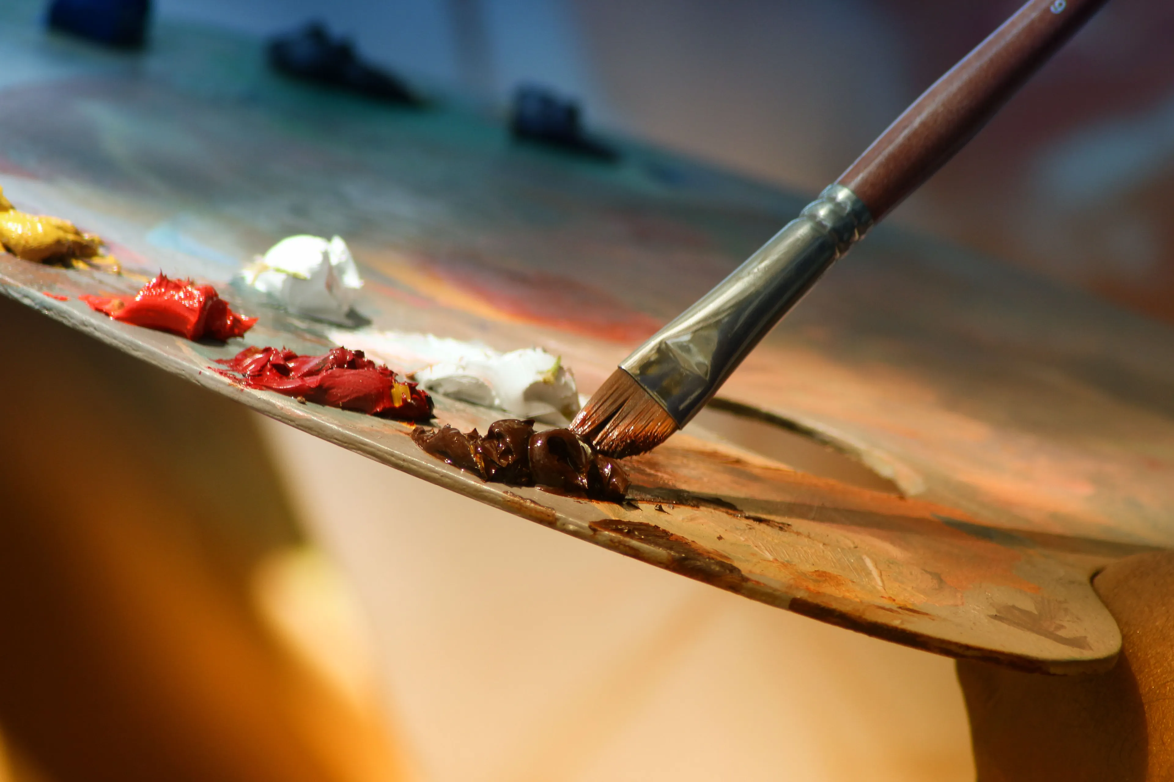 A close-up of a paintbrush on an artist's palette with various colors, representing the subject of Art.
