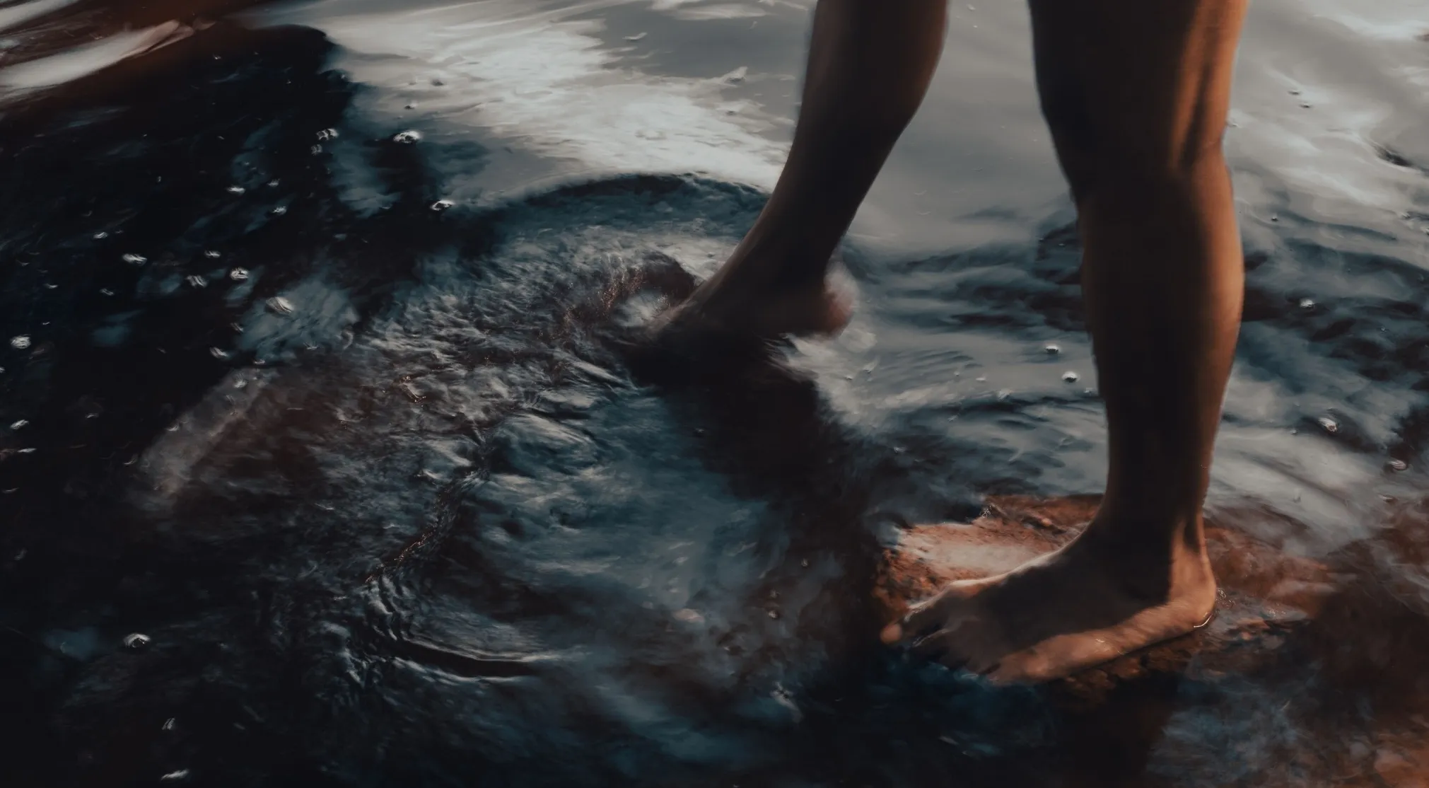 Human legs and feet standing in shallow, swirling water. How much of your human body is water?