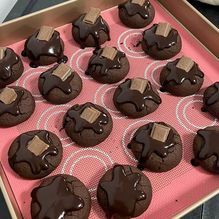 A tray of treats, dark chocolate cookies with melted chocolate and chocolate bar pieces.