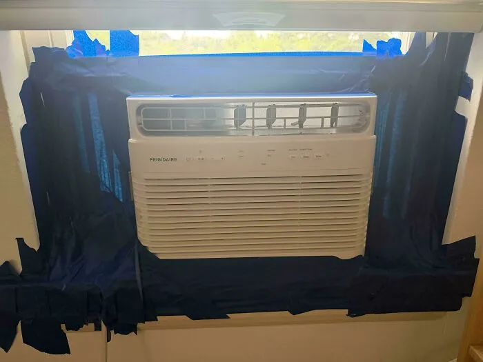 A window AC unit with fabric taped around it to seal gaps, a clever solution to improve efficiency.