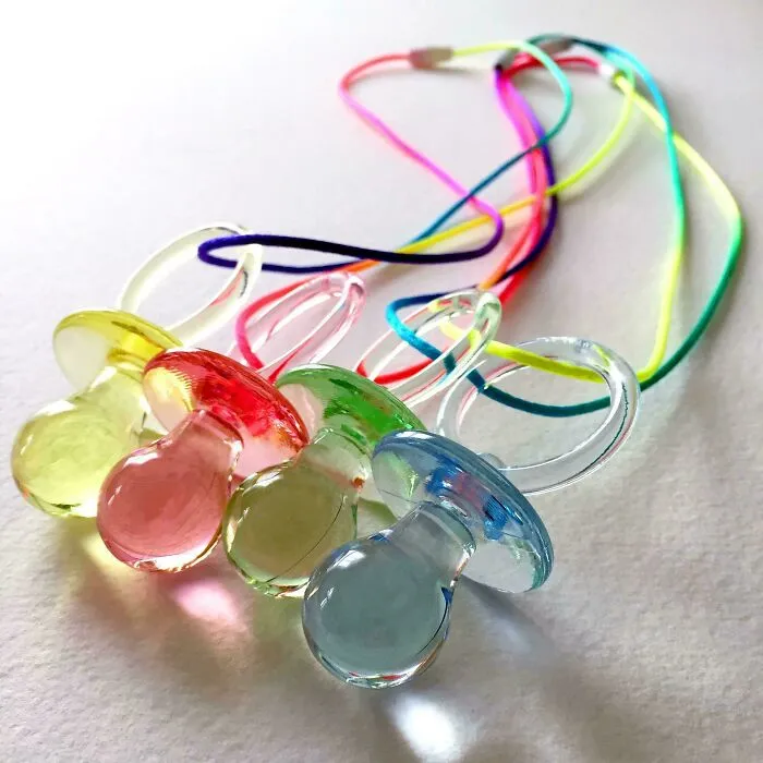 Colorful pacifier necklaces, a popular accessory for 90s kids, shown as a throwback meme.