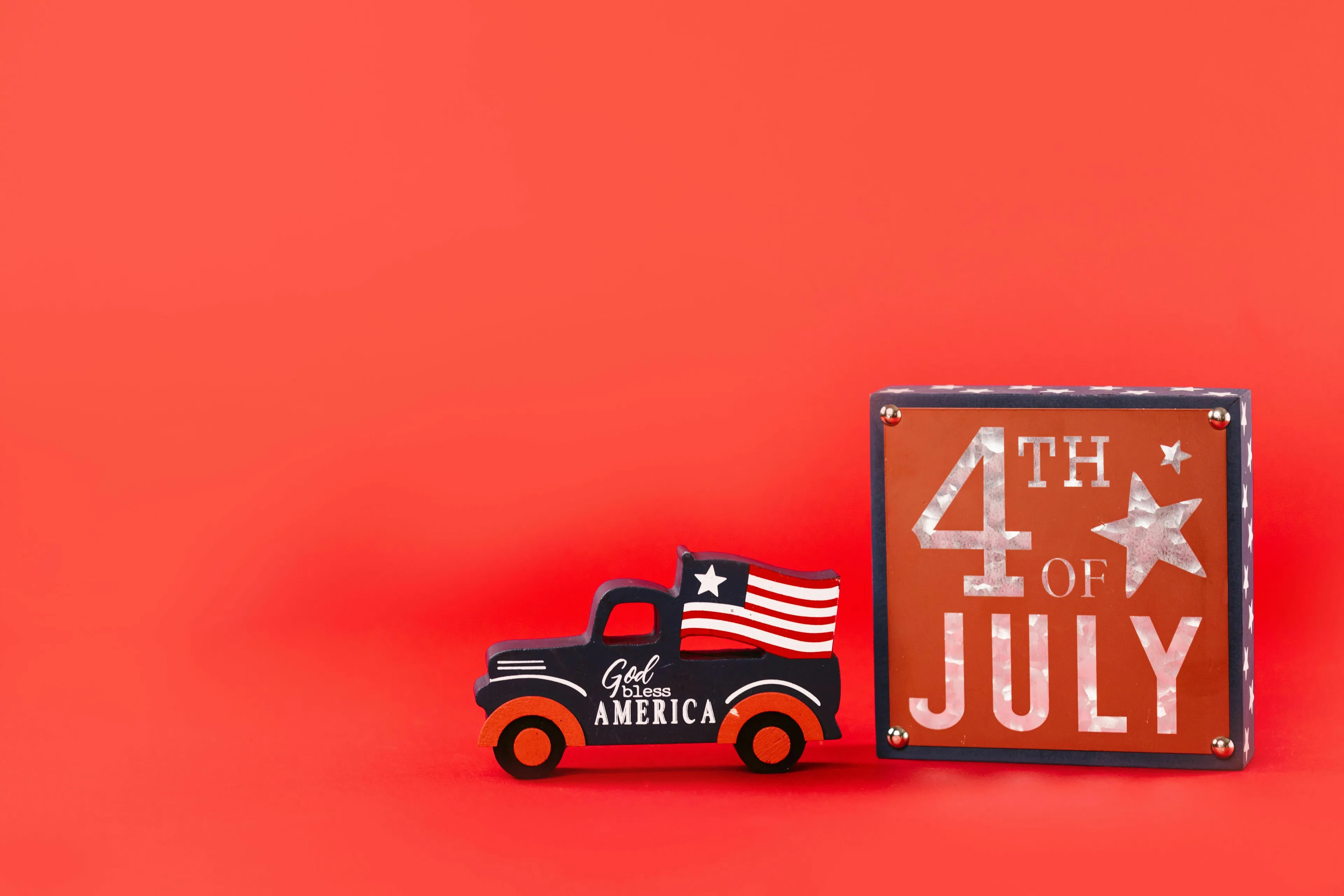 A small truck decoration with an American flag next to a Happy 4th of July sign, marking the federal holiday.