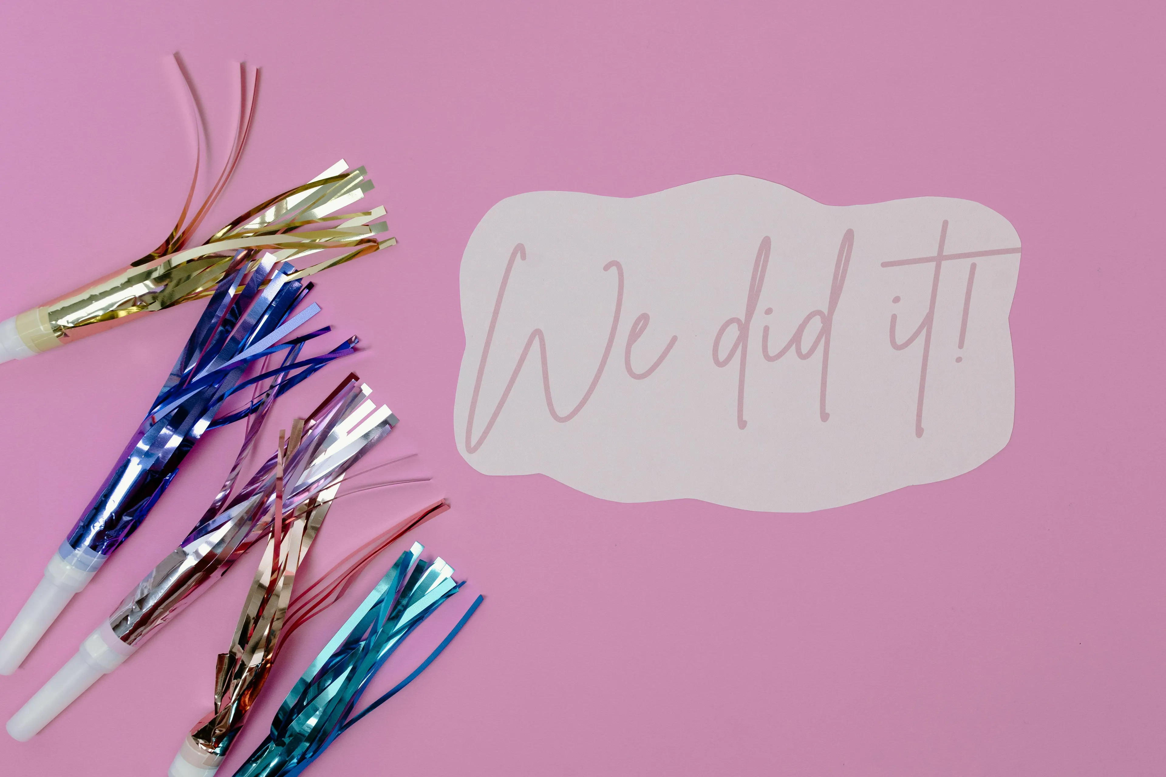 Party poppers and a speech bubble with the text We did it! on a pink background, not related to July 4th celebrations.