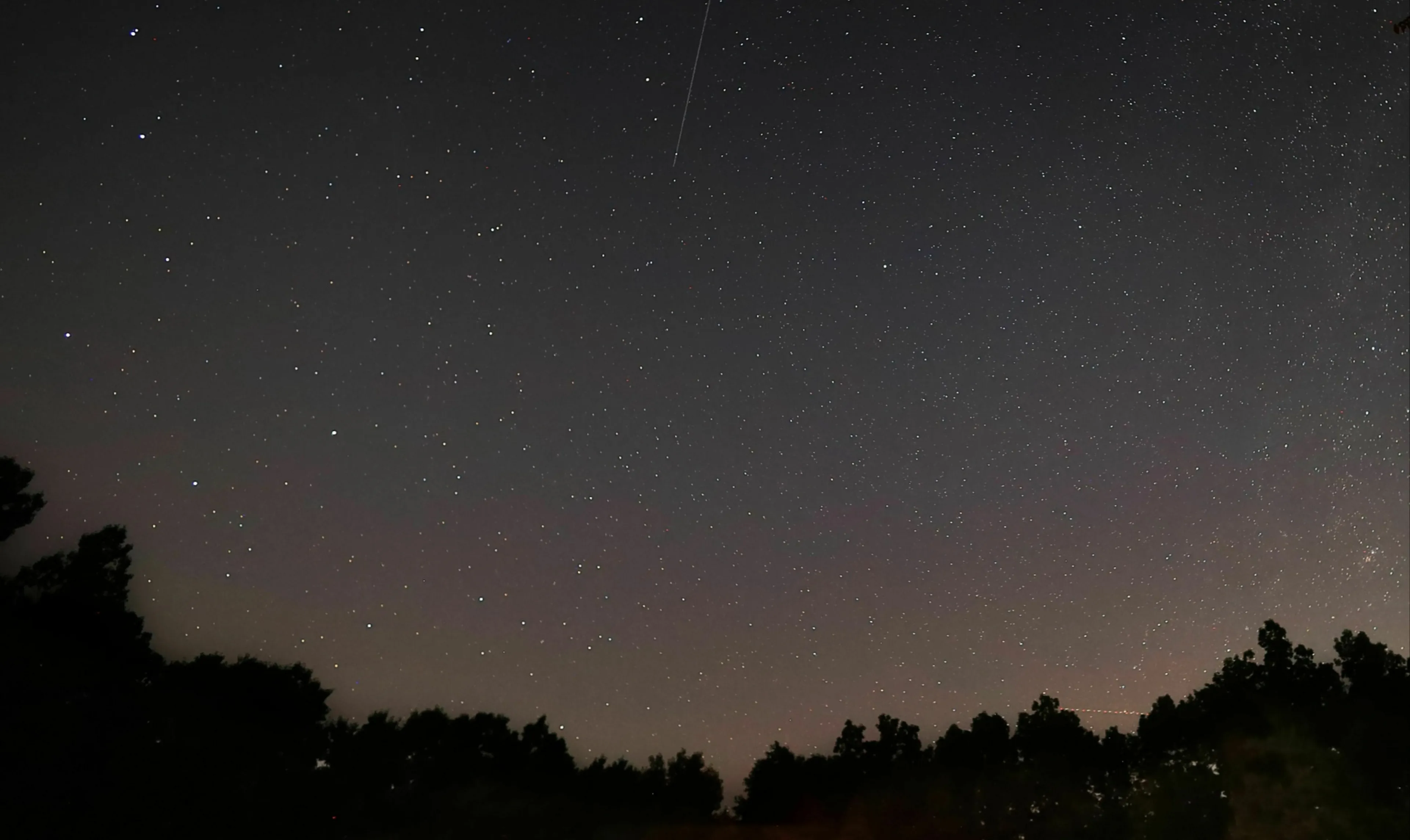 A star-filled night sky with a visible meteor, representing the star at the center of our solar system.