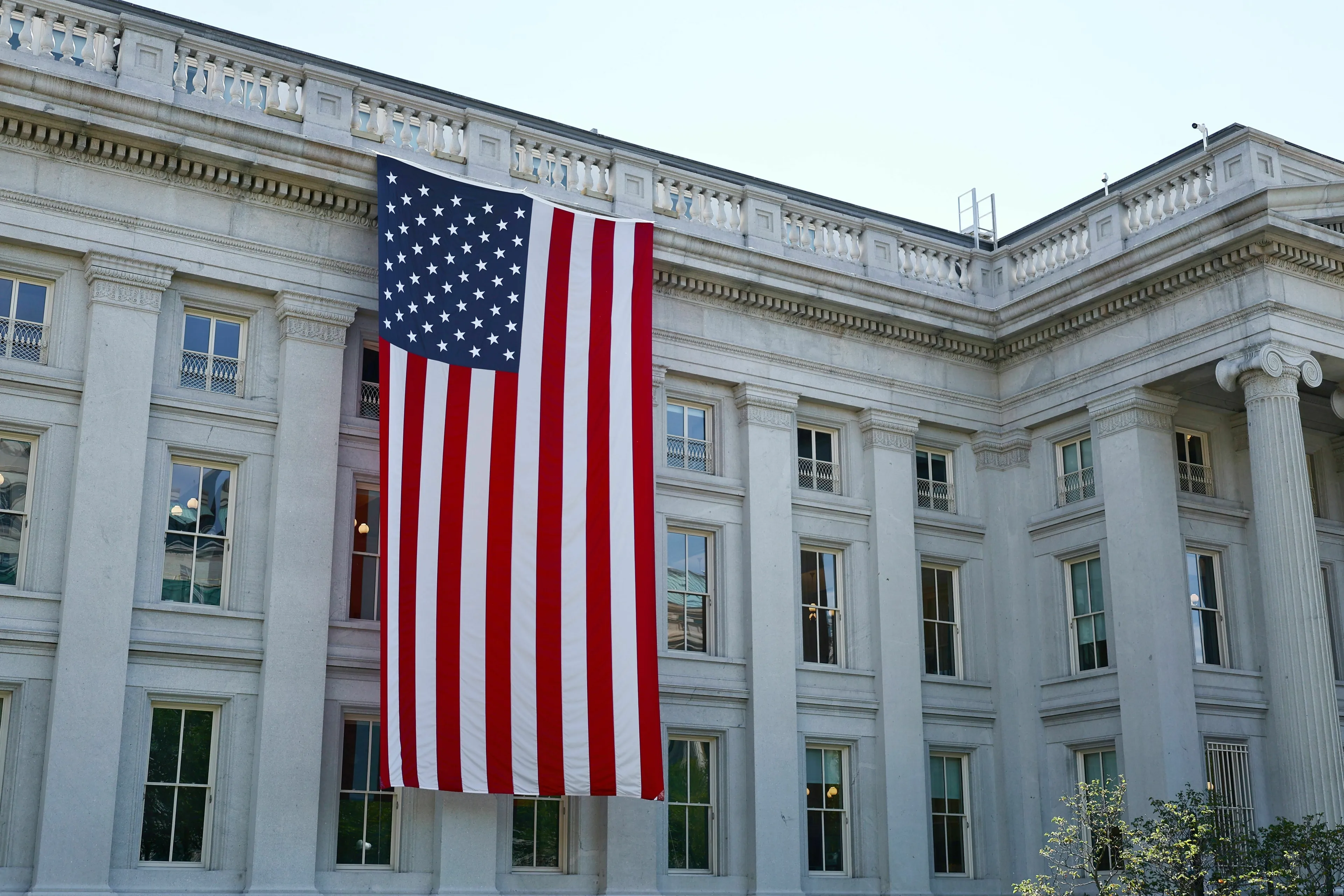 Three Letter General Knowledge Quiz: A large USA flag hangs on a government building.