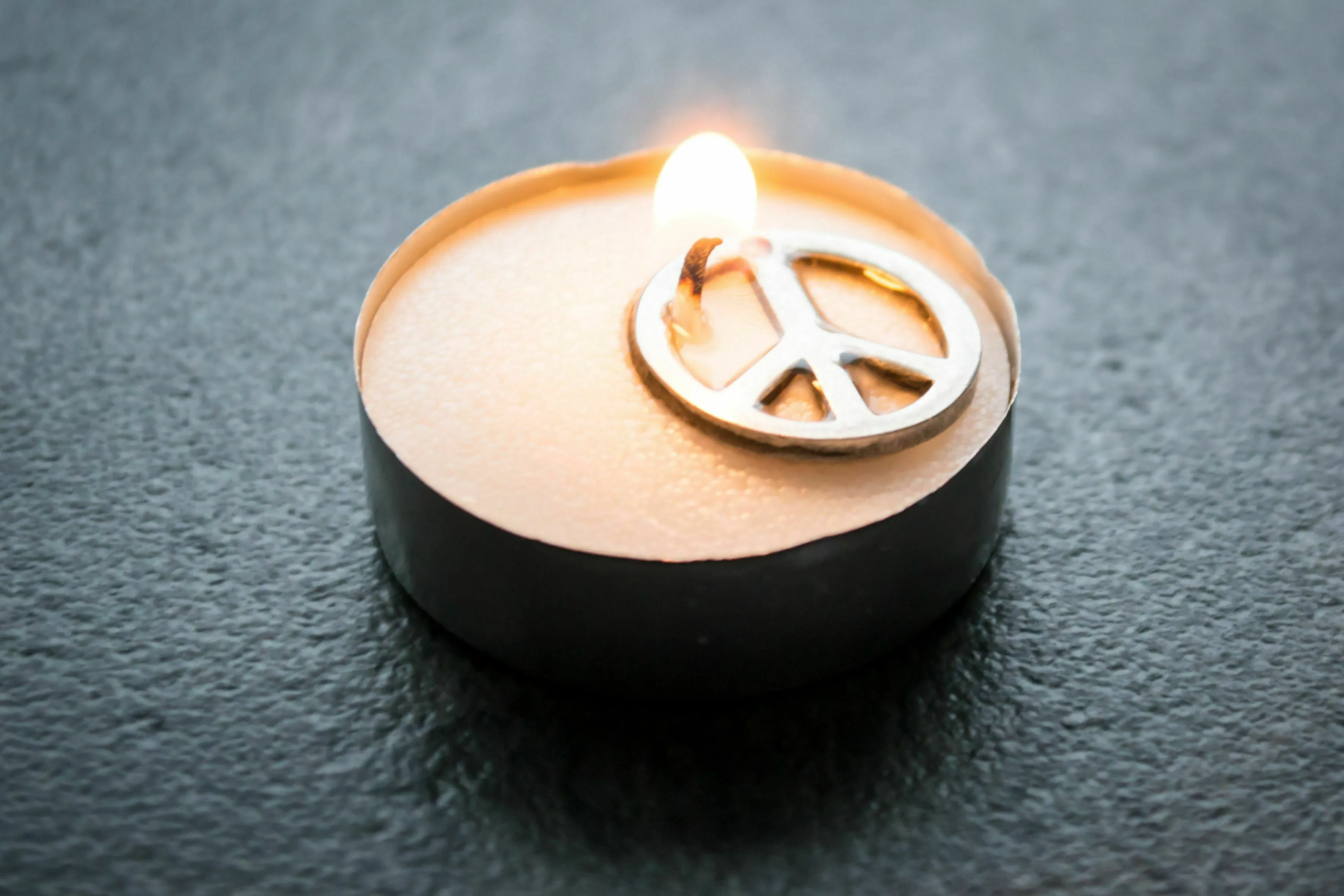 Three Letter General Knowledge Quiz: A lit candle with a peace symbol, representing the antonym of war.