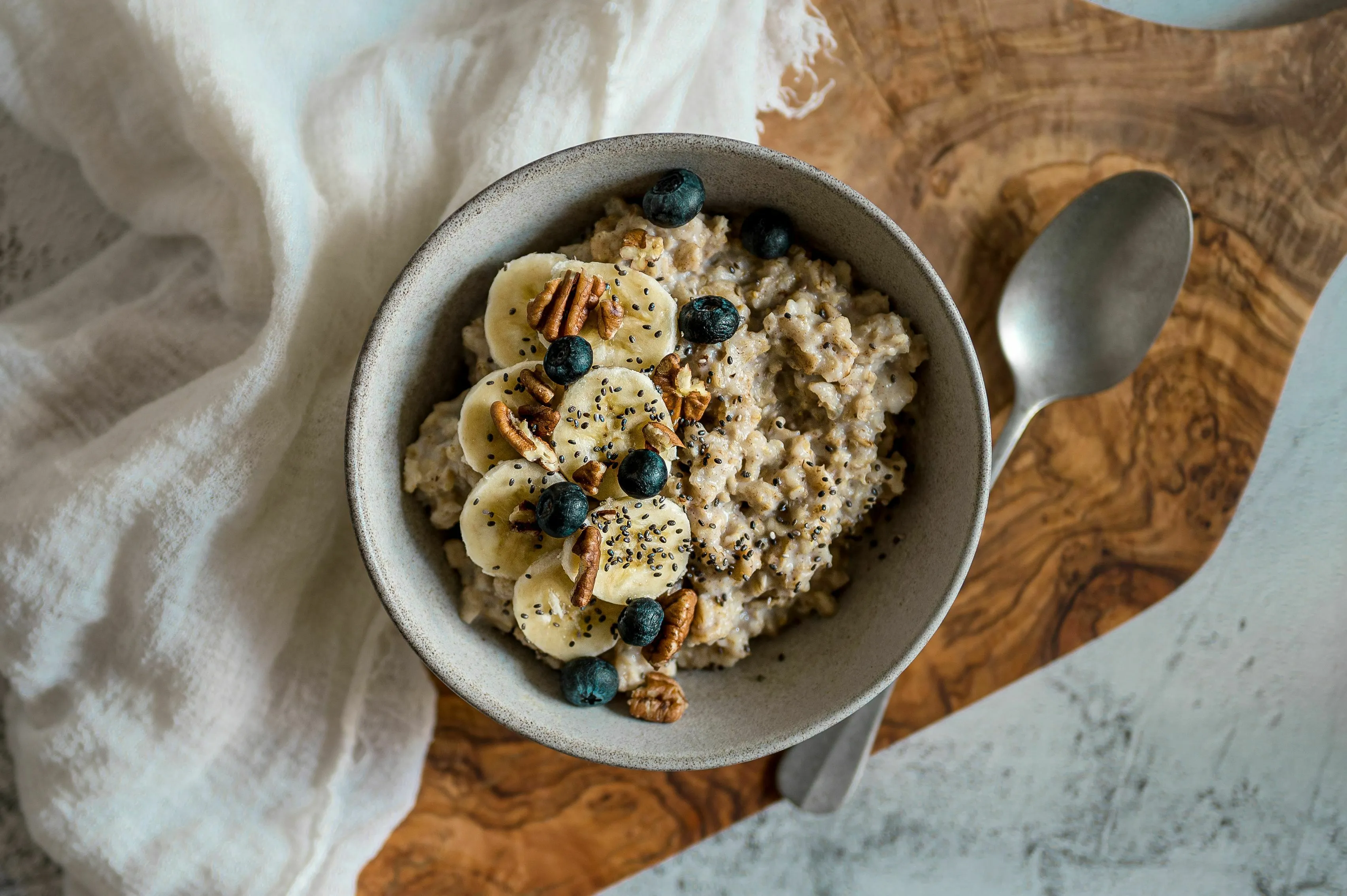 Delicious bowl of porridge topped with banana slices, blueberries, and nuts for a healthy breakfast.