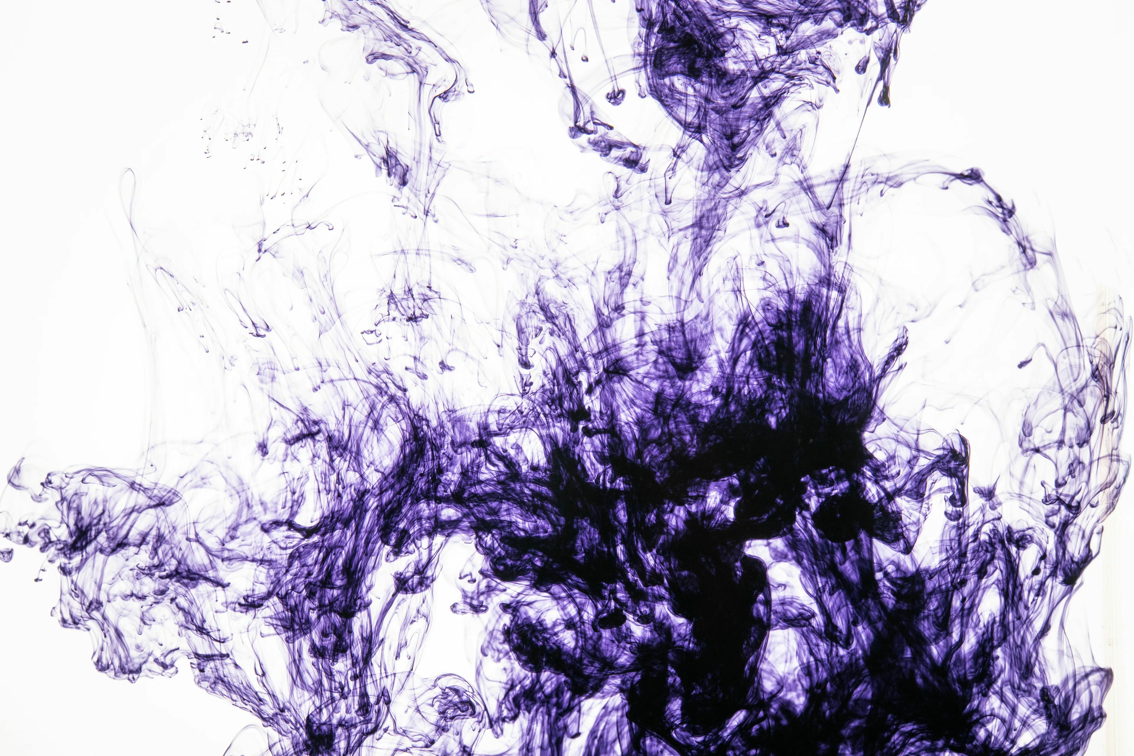 Abstract image of purple ink swirling in water, creating unique and dynamic patterns.