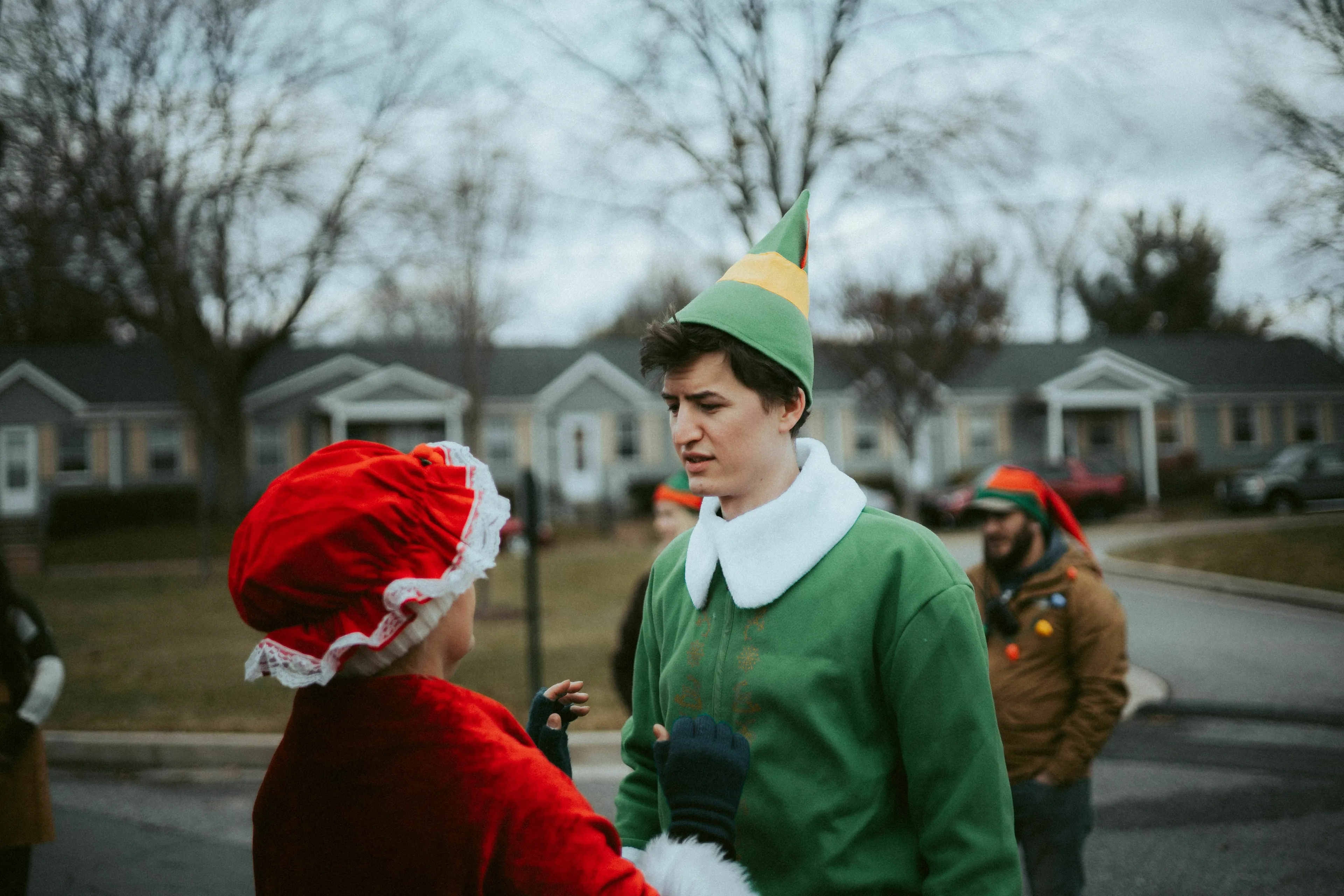 A person dressed as an elf talking to someone in a Santa costume. A mythical creature for general knowledge quiz.