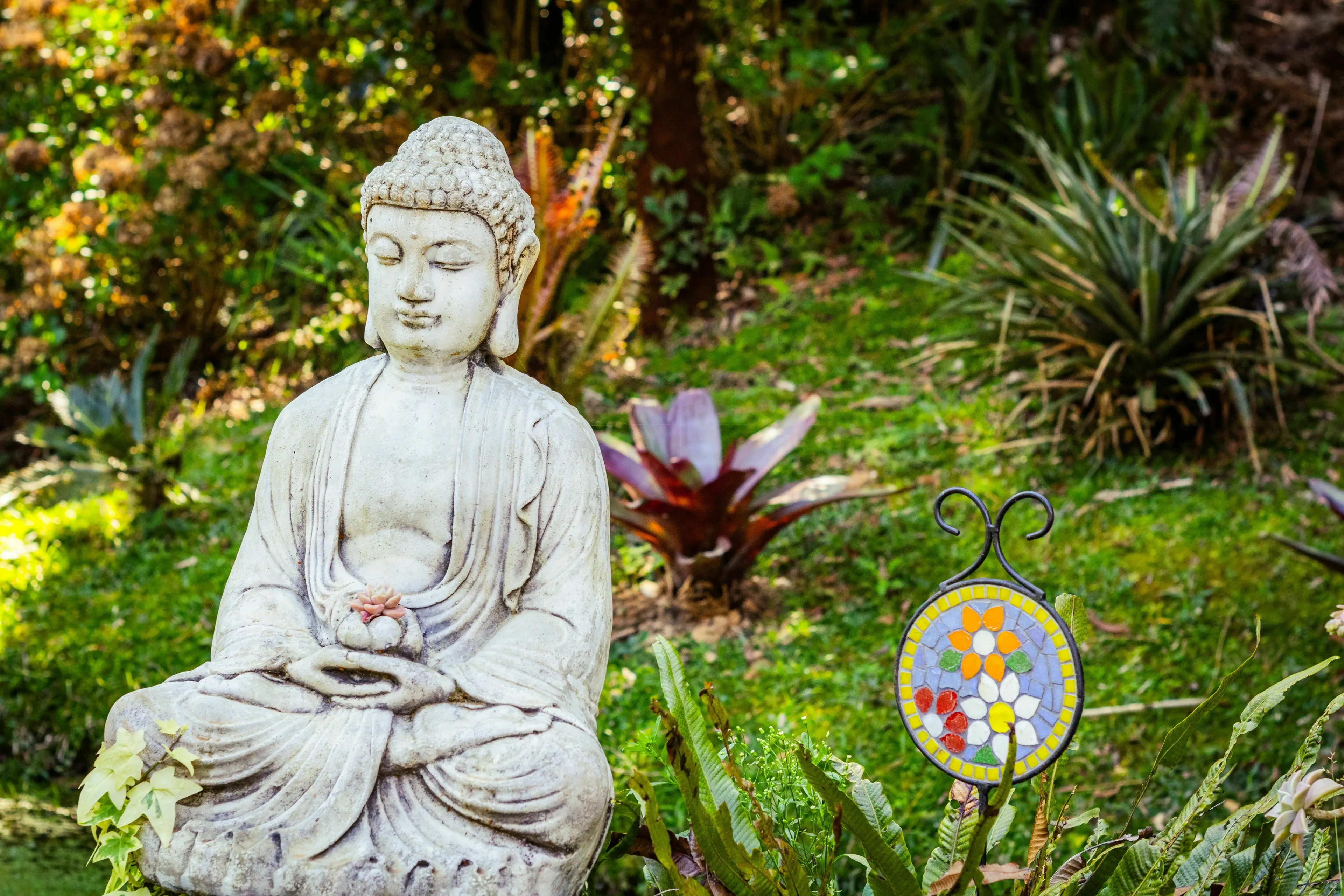 A Buddha statue in a lush garden, representing the Japanese school of Buddhism, Zen, emphasizing meditation.