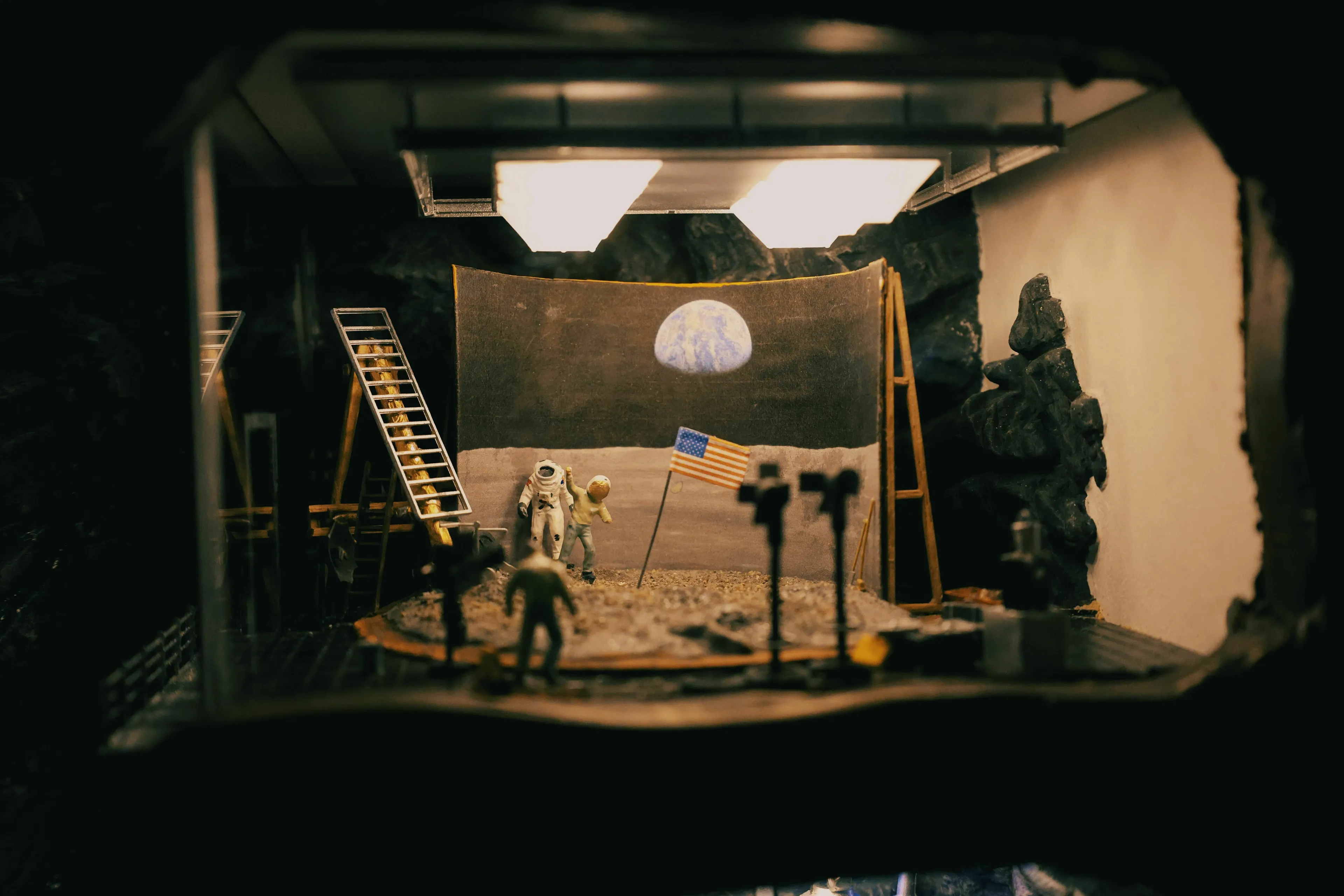 A miniature diorama depicting the moon landing, complete with astronauts, flag, and Earth in the background.