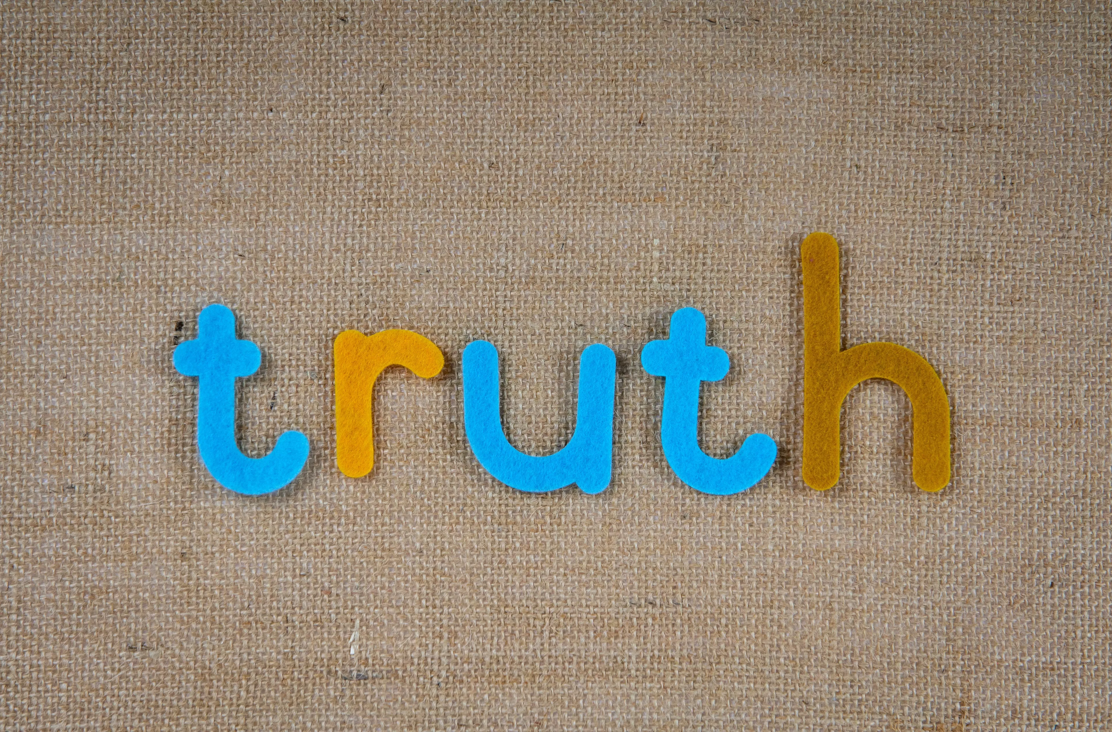 The word 'truth' spelled out in colorful felt letters on a burlap background, representing a belief.