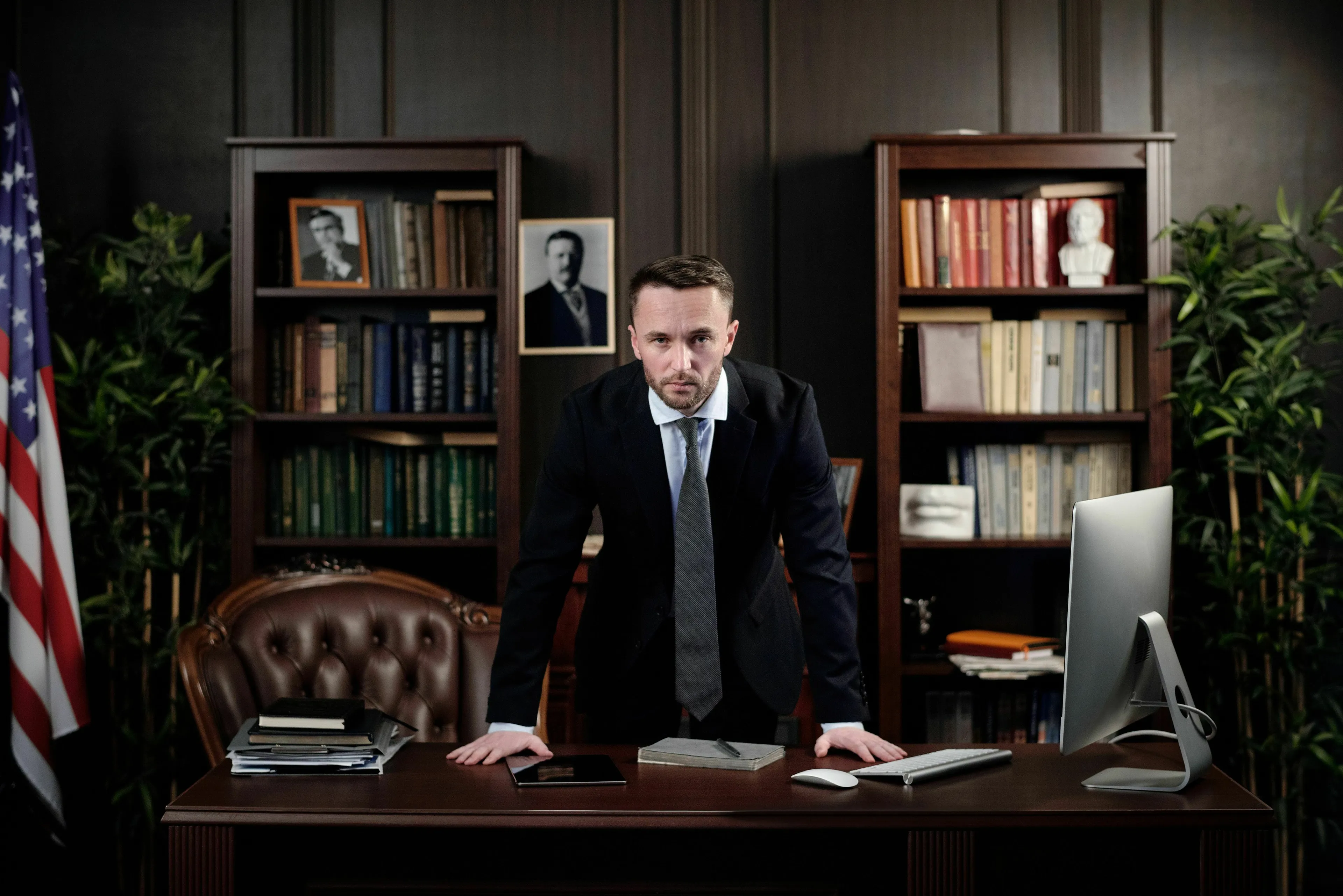 A man in a suit behind a desk in a power-filled office, considering positions of extreme power.