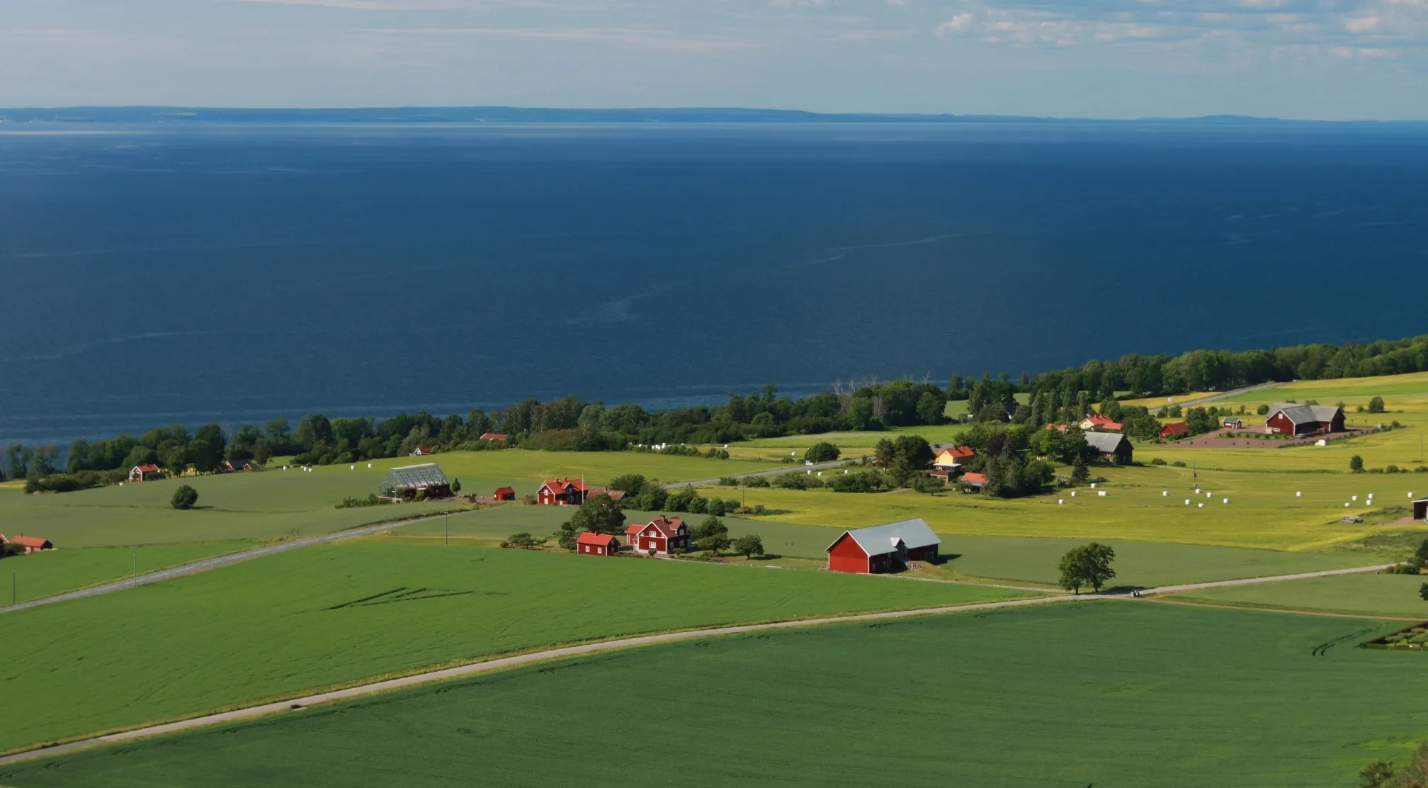 An aerial view of a European countryside with green fields, red barns, and a blue lake. Which European country has the most islands?