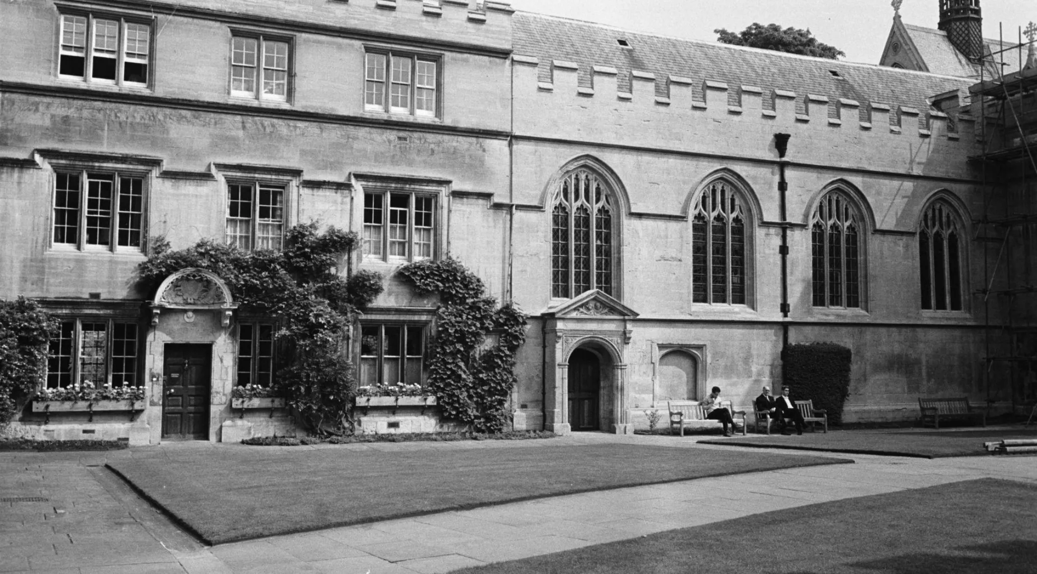 Black and white image of an Oxford University courtyard with two people sitting on a bench, part of Match The Answer To The Question.